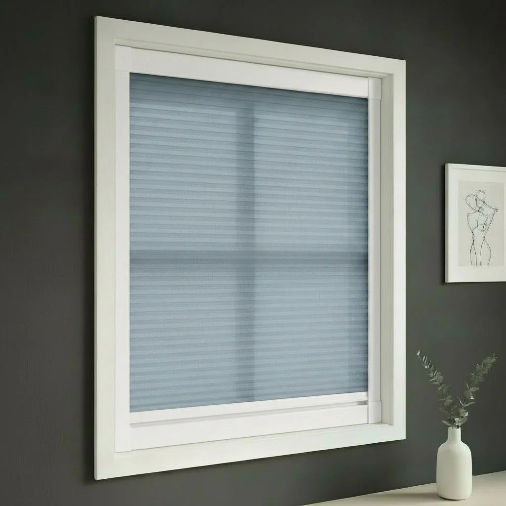 FAIZ light filtering cellular blind in Blue fabric with White rail, shown for softer evening light before sleep.
