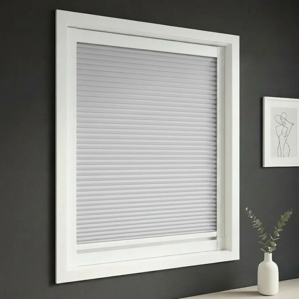 FAIZ blackout cellular blind in Light Grey fabric with White rail, shown for a restful home interior and complete darkness.