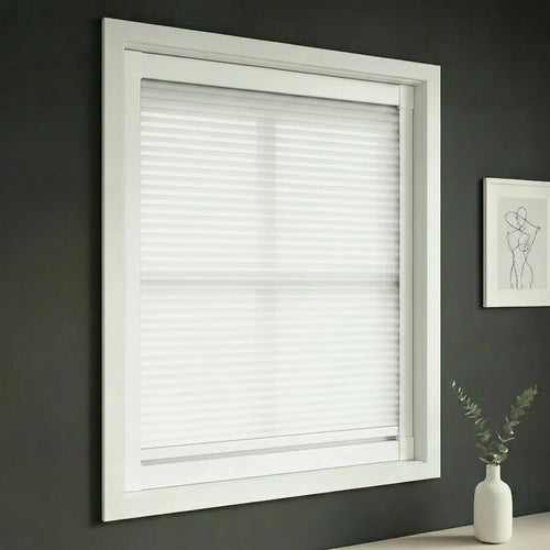 FAIZ light filtering cellular blind in White fabric with White rail, shown for soft daylight and a calm bedroom.